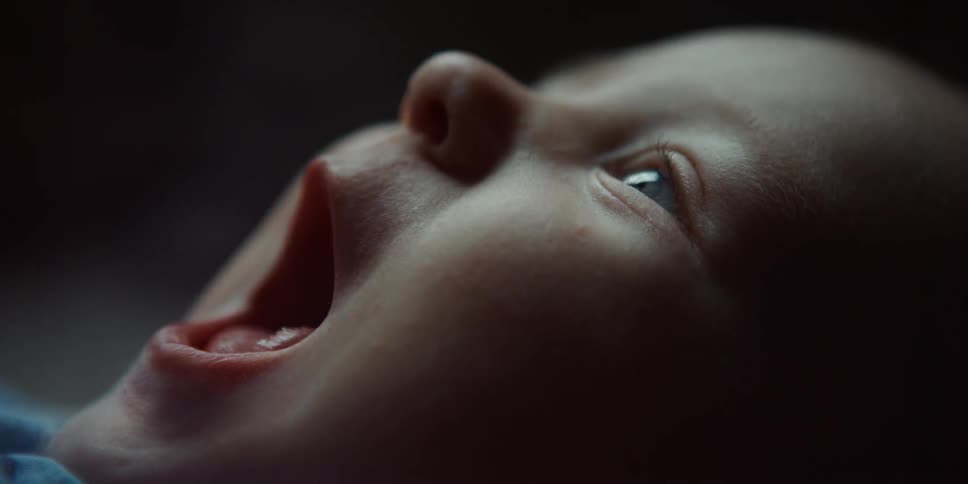 Close up of the face of a baby laying on its back yawning