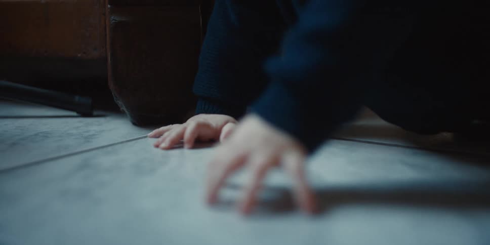 Baby wearing long sleeved shirt crawls across pale tiled floor
