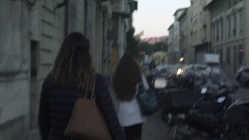 People walk down a road in a city