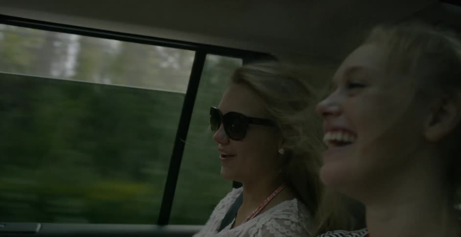 Two girls talk in the back of a moving car