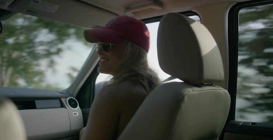 Woman in a red hat laughing in the passenger seat of a moving vehicle