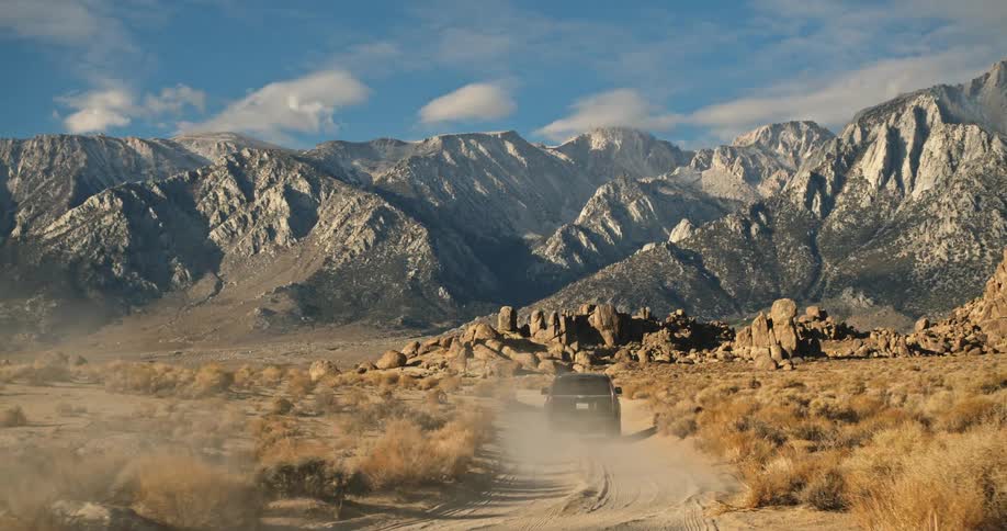 Black suv driving on dirt trail through the desert