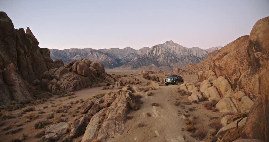Sports utility vehicle parked on a road in rocky terrain against a mountain range