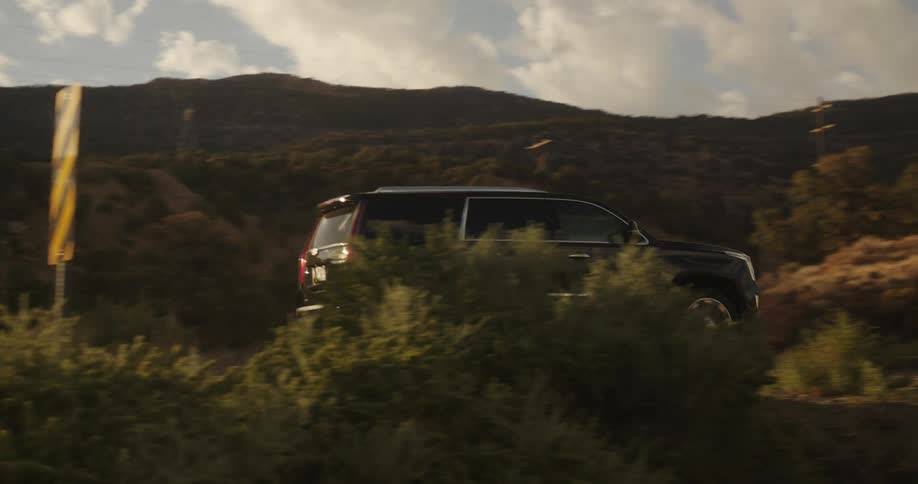 A large personal vehicle is driving through a high desert area