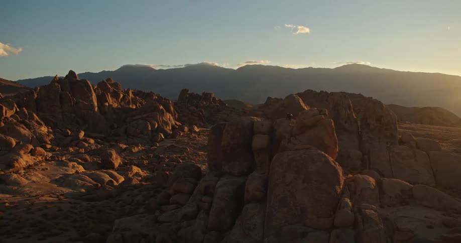 Rocky terrain in front of mountains under clear skies with scattered clouds