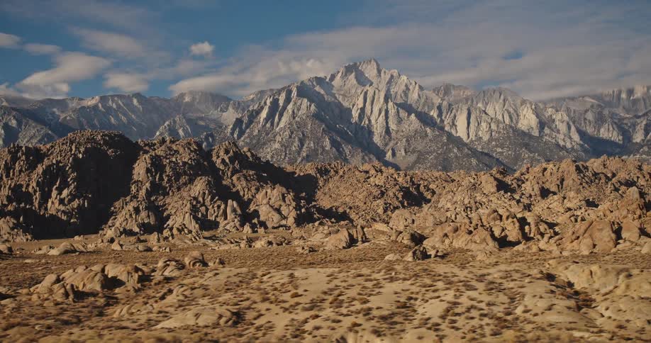 A distant mountain range under the clouds in the desert seen from a moving vehicle