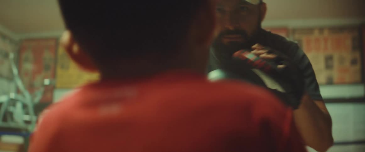 Bearded coach teaching a young boy how to box on a gym
