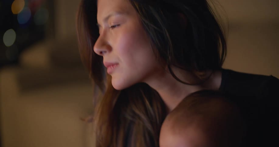 Baby in a black shirt sits on a womans lap indoors