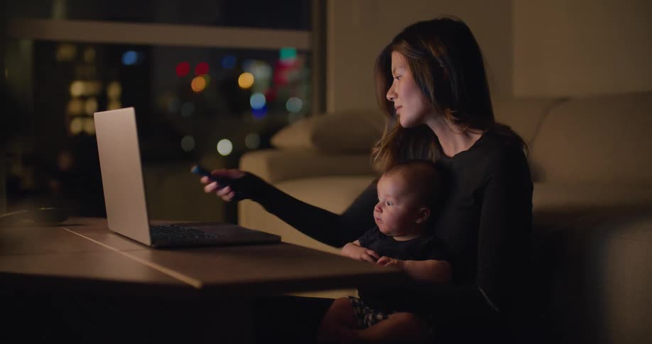 A mother and baby are sitting down and are using the laptop