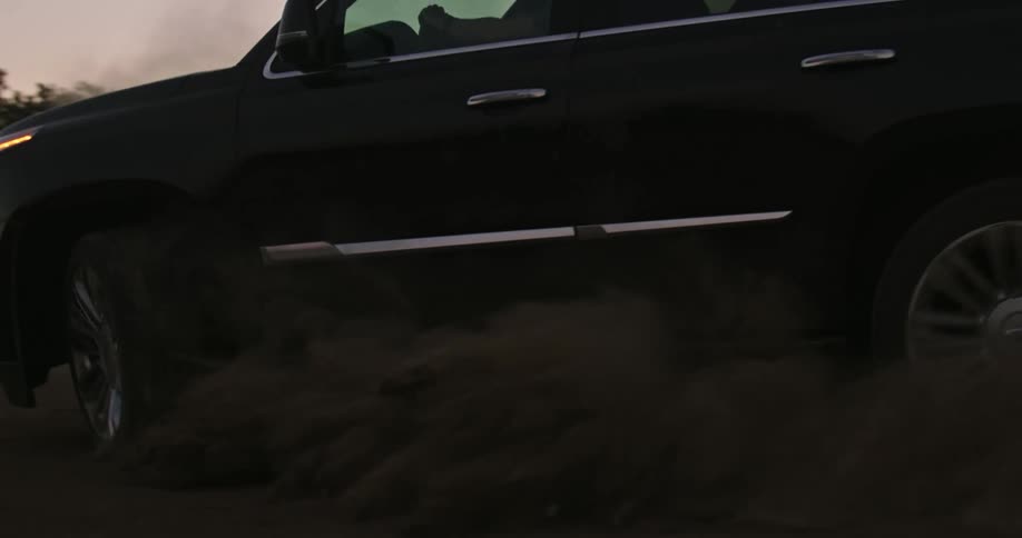 Black suv driving on the dust in the countryside at evening