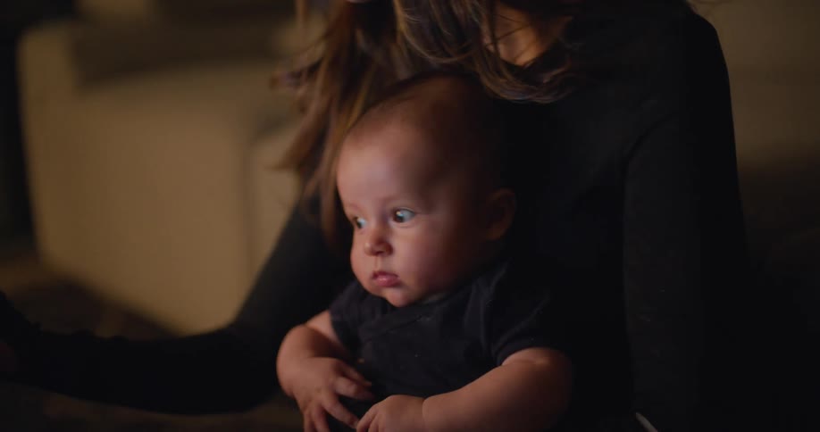 A mother is holding her baby and sitting down