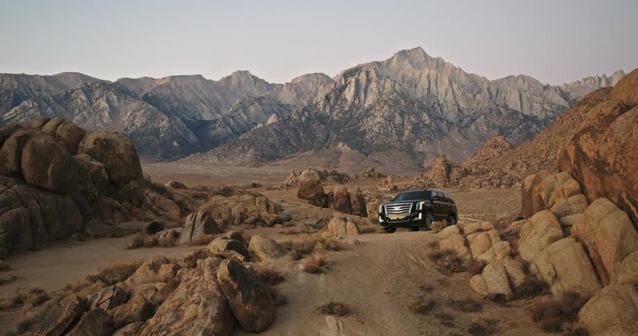 Black suv parked on a rural road in the mountains on a desert at evening