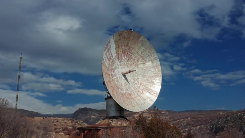 An old satellite dish is on top of a mountain
