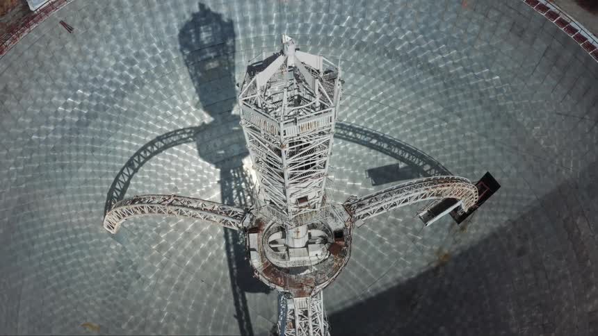 Aerial orbiting view of the tower on the center of a radio telescope
