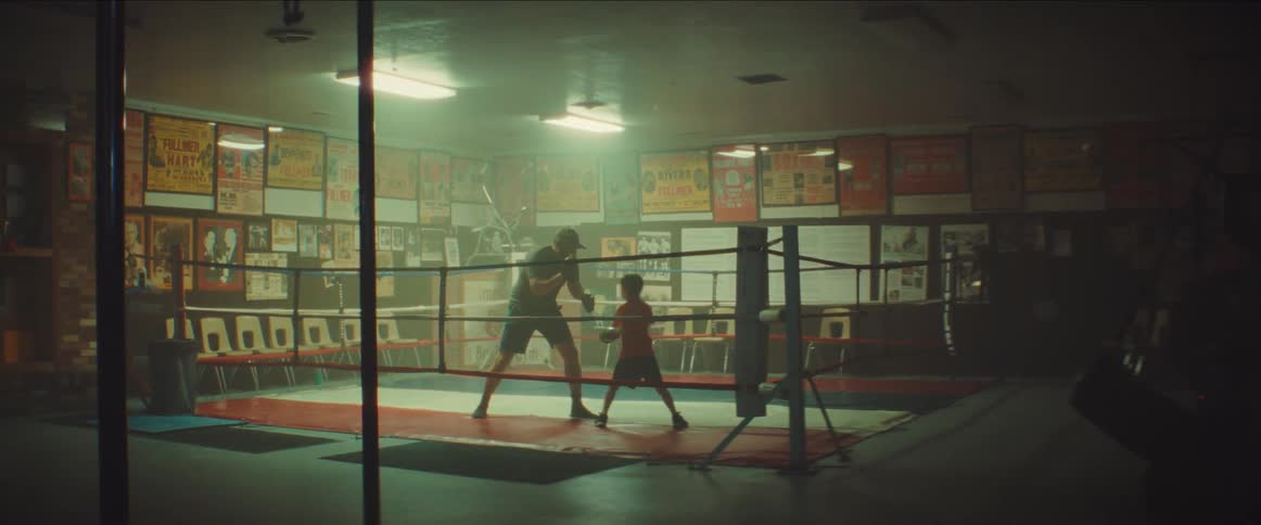 A man is teaching a young boy how to box in a boxing ring