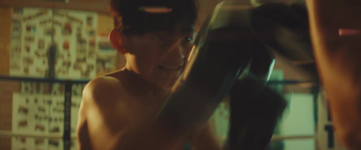 Man trains boy in boxing ring in boxing gym with an open door