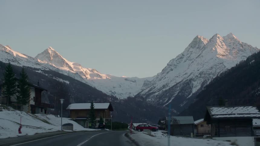 Driving down a snowy road toward the mountains