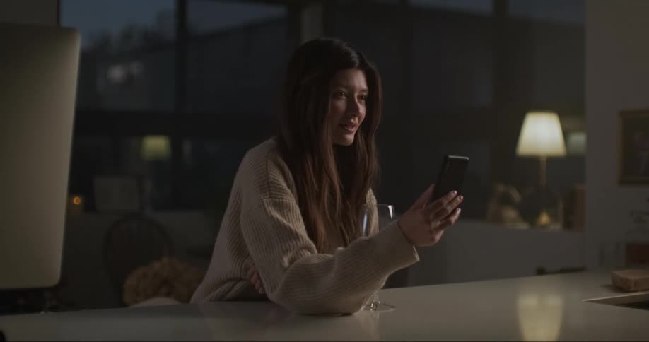 A young woman is sitting down and looking at her phone