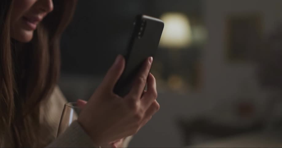 A woman is sitting at a table holding her phone and talking