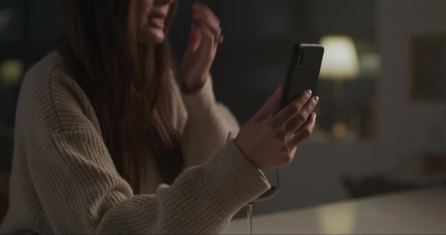 A young white woman in sitting down on her phone and drinking some wine