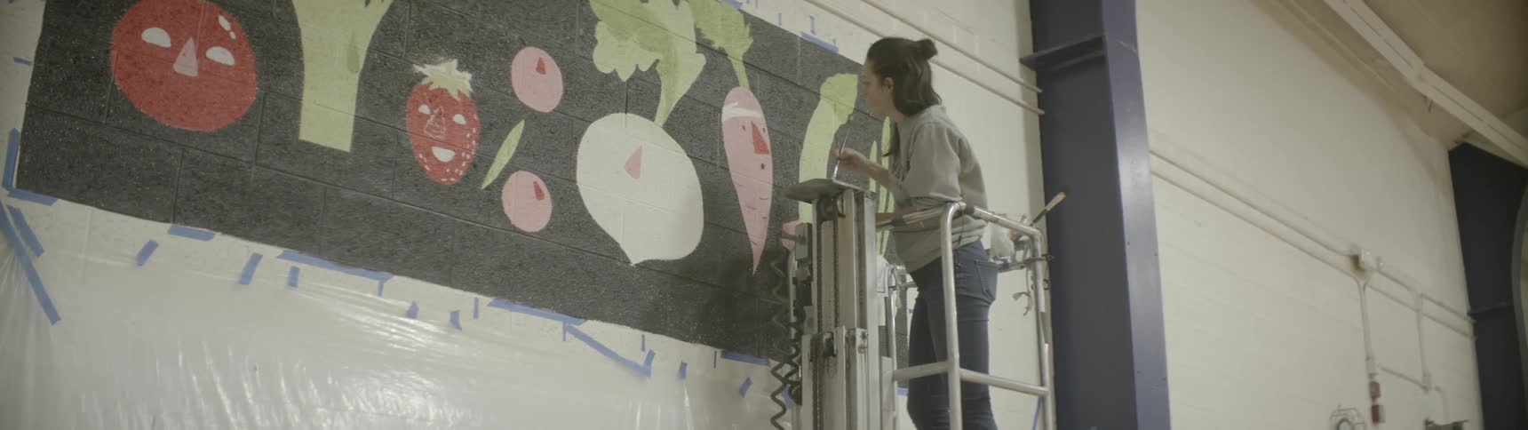 A woman paints a carrot on the wall