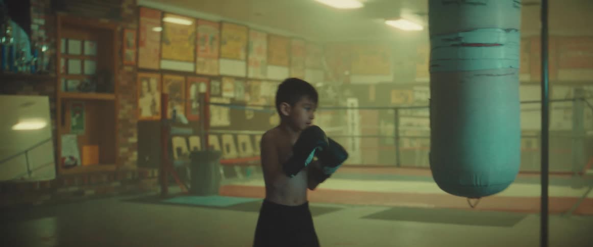 A boy trains by striking a punching bag in a boxing gym
