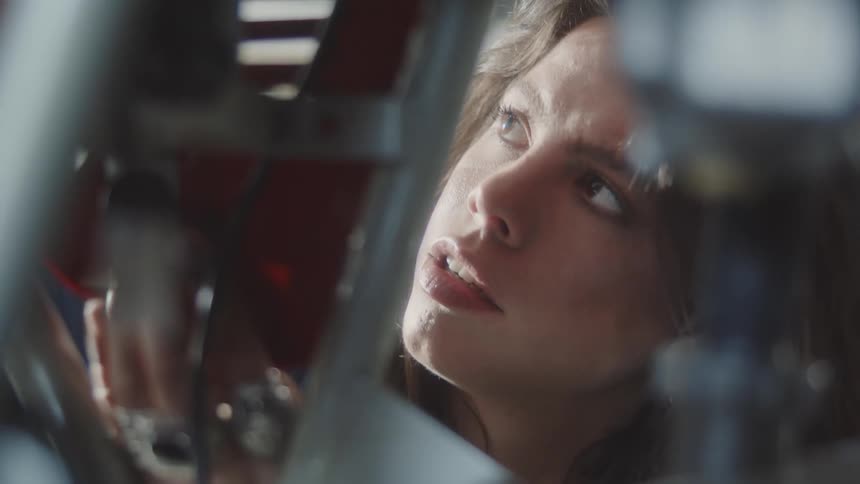 A young female mechanic fixes the engine of a motorcycle inside an auto shop