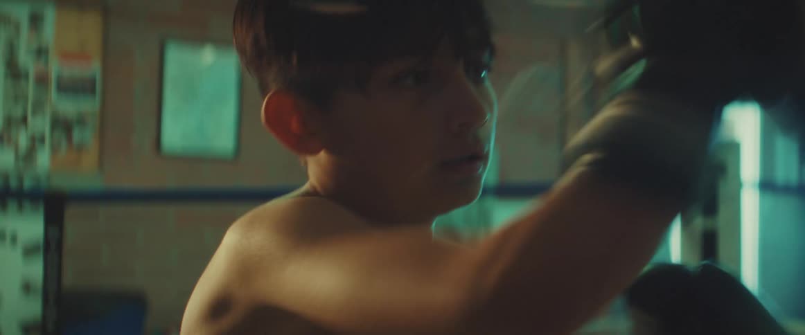 Young boy practices boxing with a coach at a gym