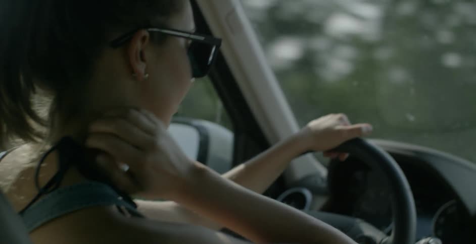 A woman scratches her neck while driving