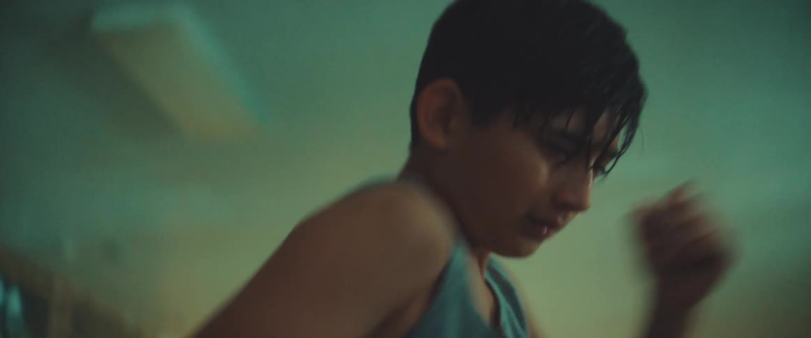 Sweaty young boy shadow boxing indoors in a gym