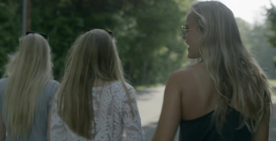 Three blonde women walk down the road