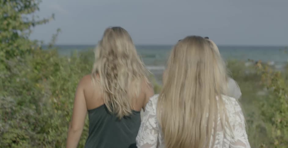 A group of women walk down a bush lined path