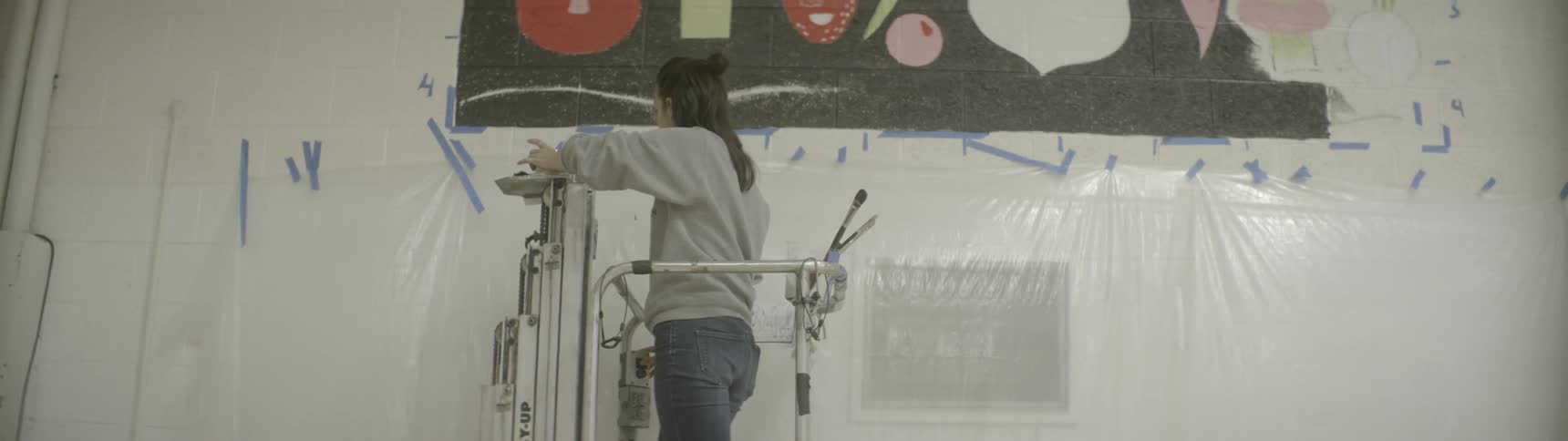 A woman on an electric lift prepares to paint a mural