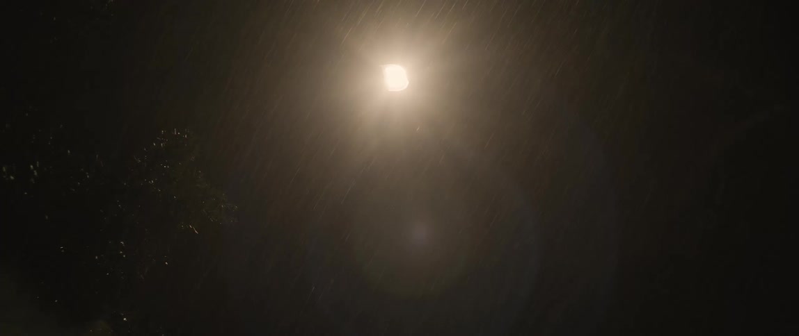 Lightning brightens clouds over streetlight during thunderstorm