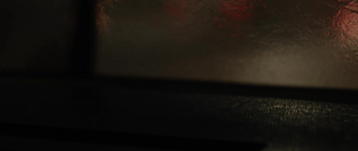 Windshield wipers wipe rain allowing blurry view of taillights