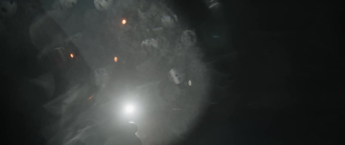 Water droplets over the rearview mirror reflecting the headlights of moving cars at night
