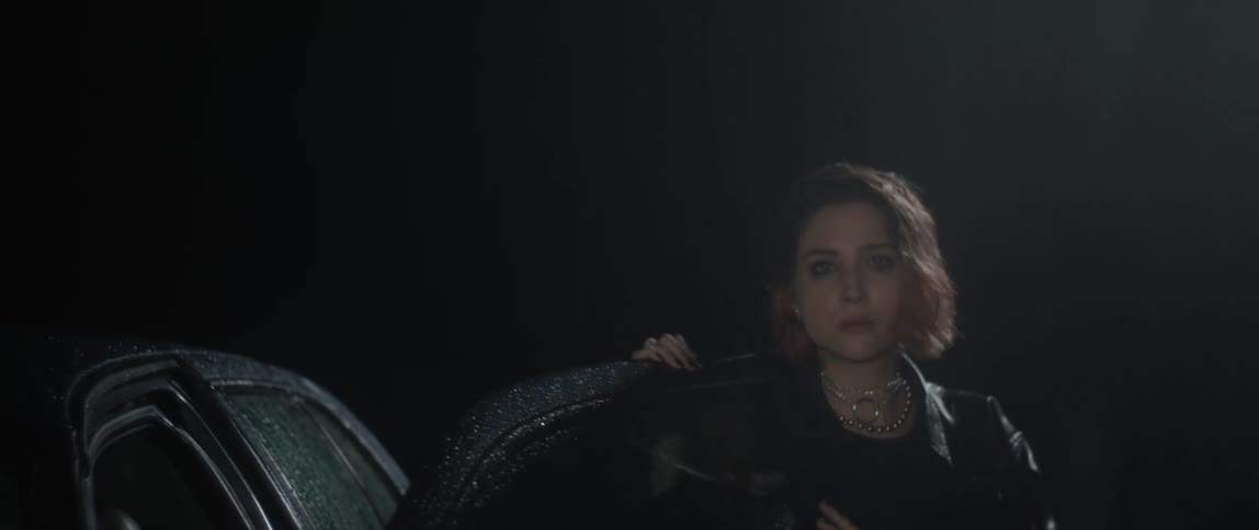 Woman with short hair exits car and steps into the dark rainy atmosphere