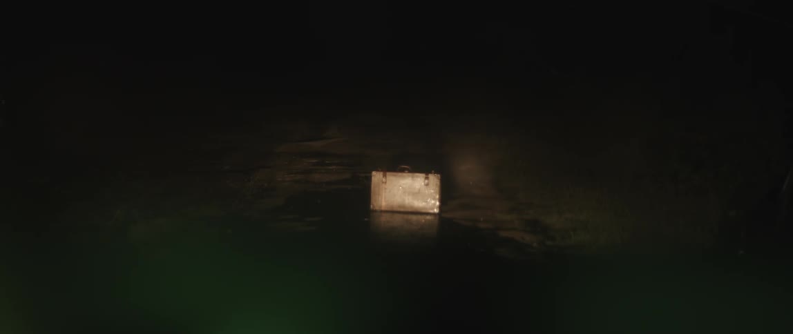 Abandoned suitcase standing on the middle of the road at night under rain