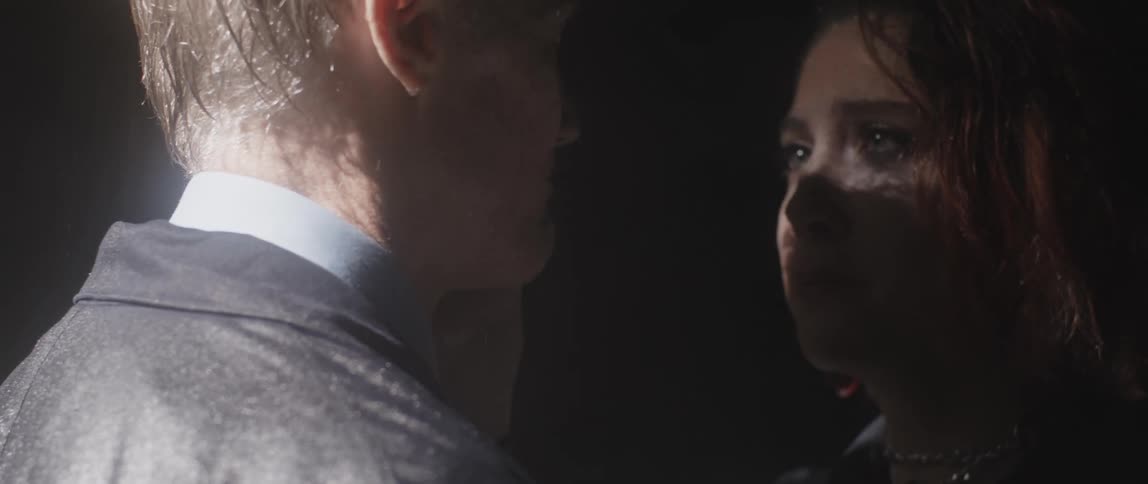 A man and a woman are standing in the rain and embrace