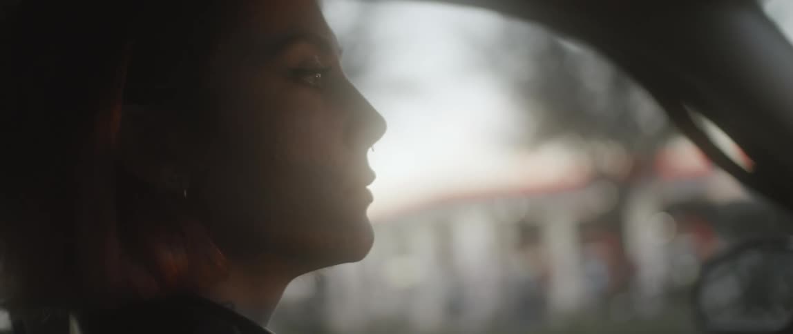 Close up of the face of a woman driving a car on a small town at morning