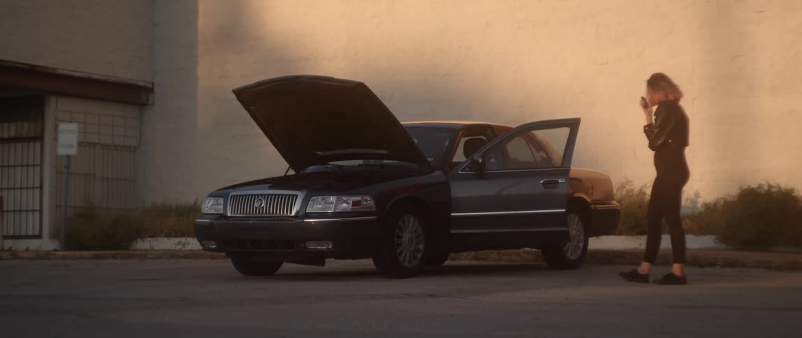 Woman yells into smartphone then paces back and forth near stalled car with its hood up