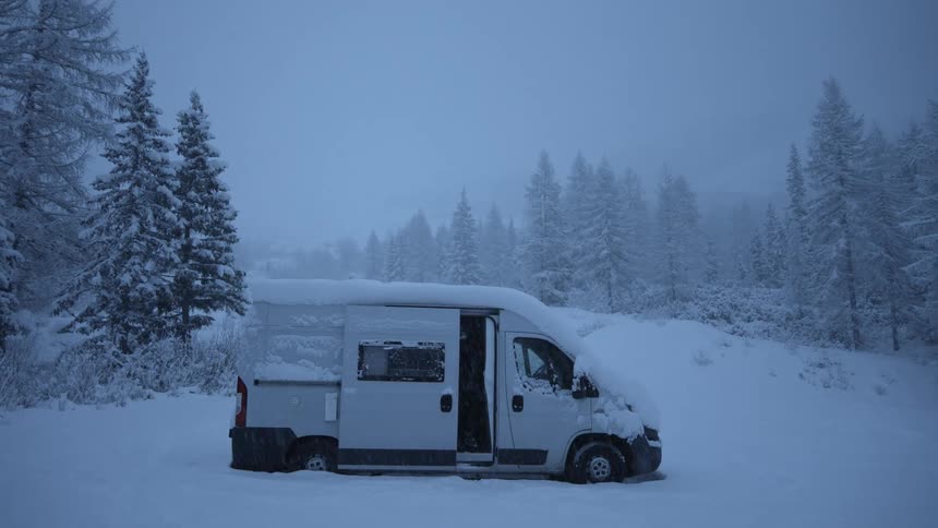 There is man that is coming out of his vehicle in the middle of a snowing area