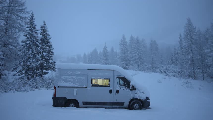 The interior light comes on in a camper van parked near a forest
