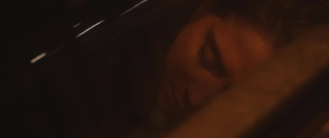 A woman pulls a blanket up as she lays down to sleep