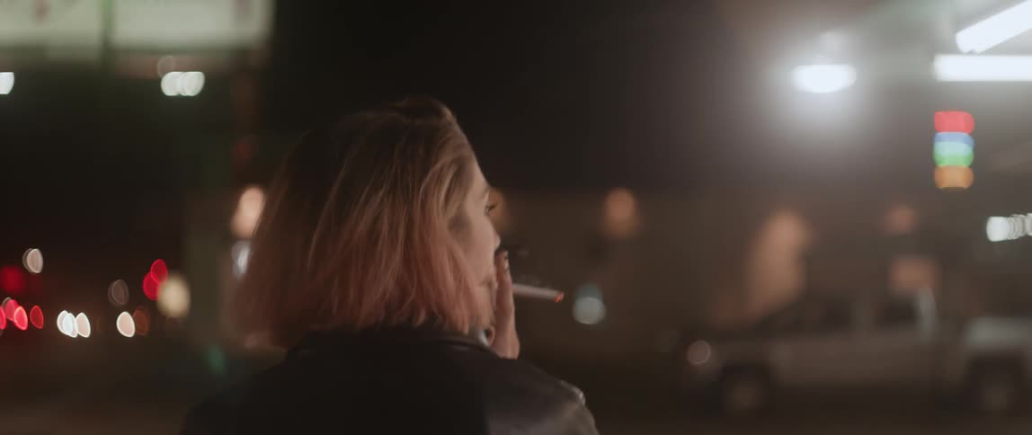 A female is walking in a city smoking a cigarette