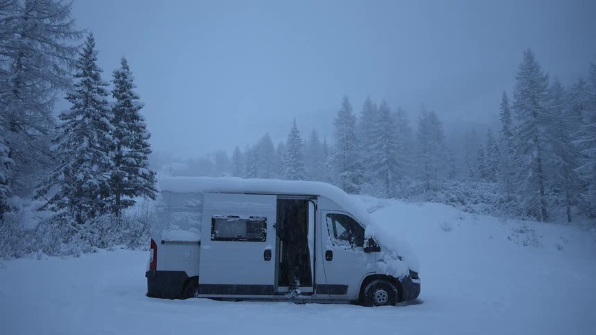 A person is getting out of there car in the middle of a snowing area