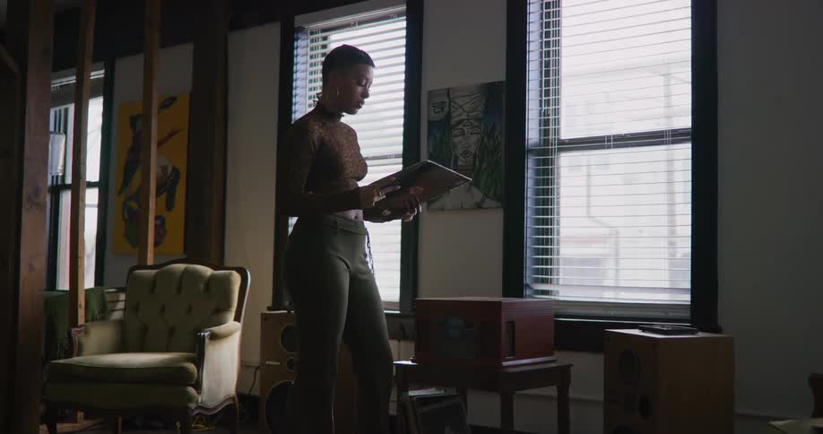 A young black woman is standing up inside of her room