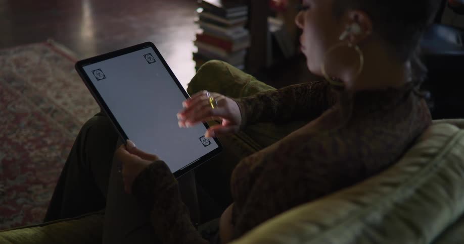 Woman sits and listens to music while using tablet