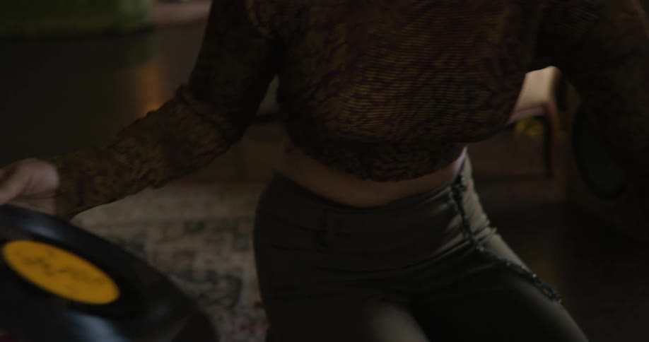 Woman is choosing an album to play on a record player in the living room