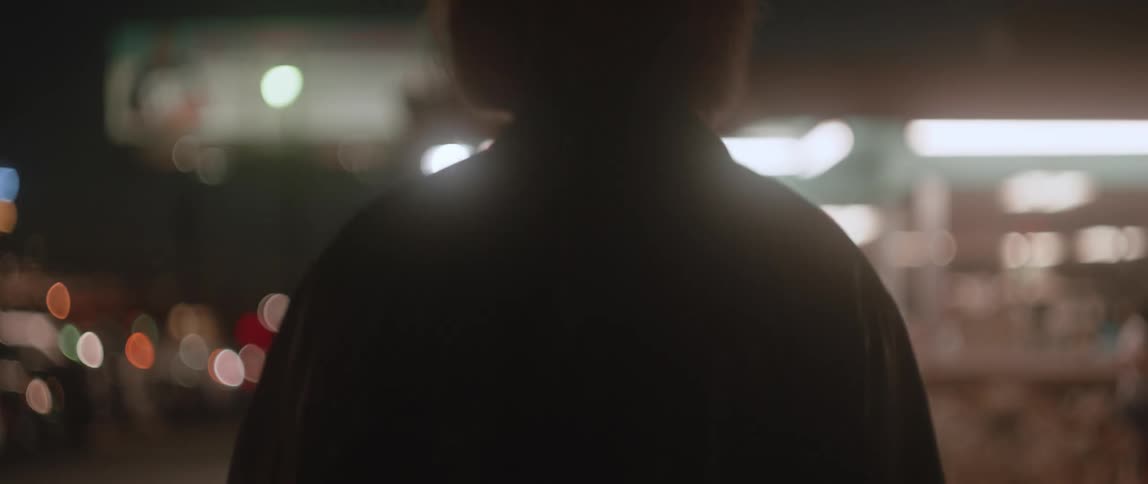 Close up of the face of a woman lighting a cigarette and walking on the streets of a small town